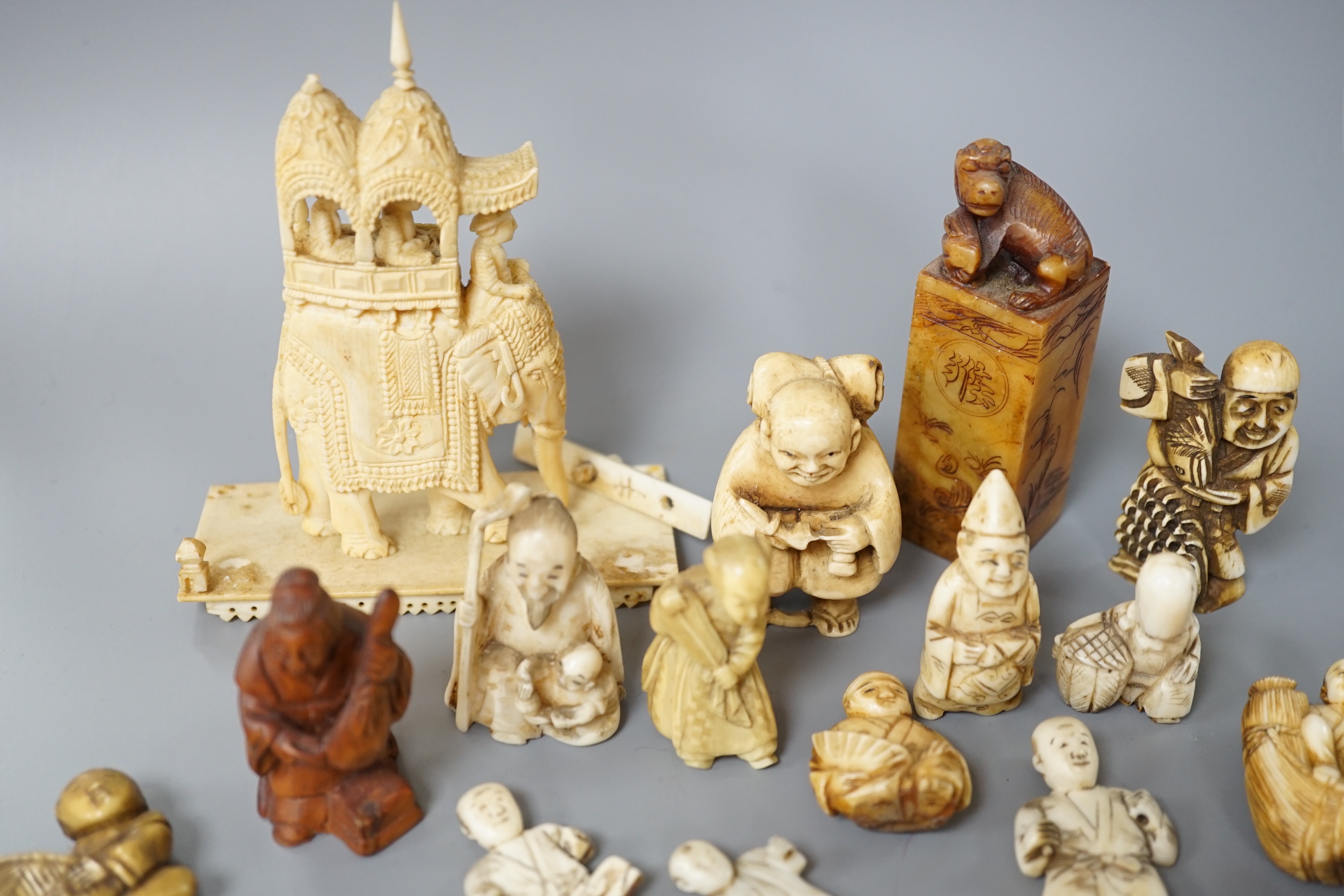 A collection of various ivory carvings including netsuke, a soapstone seal and carved wood netsuke